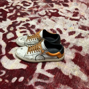 Oliver cabell - Snygga vita sneakers med orange häl och svarta detaljer. Skorna har oranga snören och en rund tå. Ovandelen är i skinn och de har en klassisk platt sula. Perfekta för dig som gillar en unik och cool stil. De mesta är smuts som går att tvätt bort men sedan lite defekter där på som kan användas som design
