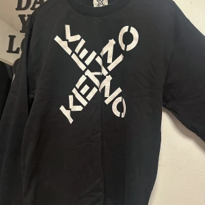Svart Kenzo sweatshirt  - Cool svart sweatshirt från Kenzo med stort vitt grafiskt logotryck över bröstet. Köpt för 1000kr men använda bara en gång