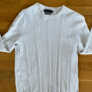 Vit kabelstickad tröja från Riley - Säljer en vit kabelstickad tröja från Riley i premium bomull. Tröjan har rund halsringning, lång ärm och klassiska flätade detaljer framtill. Perfekt för dig som gillar en clean och stilren look och en riktigt fin passform 🙌🙌🤝💠💠