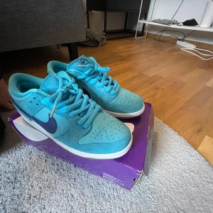 Nike SB Dunk Low Pro (blue fury) - Nike SB Dunk Low Pro sneakers i en fräsch turkosblå färg med mörkblå swoosh och silverdetaljer på hälen. Skorna har klassisk snörning, perforerad tå och vit sula. Skorna är näst intill oandvönda, Perfekta för dig som vill ha ett par sköna skor till vardagen.
