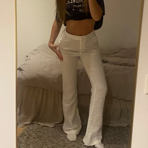 Vita vida linnebyxor hög midja - Snygga vita linnebyxor med hög midja och vida ben. Byxorna har en klassisk dragkedja framtill och är tillverkade i ett luftigt linnematerial som passar perfekt till varmare dagar. Stilrena och enkla att matcha med crop tops eller skjortor.