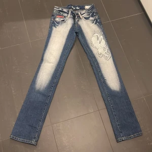 Crazy age jeans  - Snygga blå jeans från Crazy Age med coolt broderat mönster på benet och bakfickan. Jeansen har slitna detaljer och ljusa partier framtill, klassisk femficksmodell och raka ben. Perfekta för dig som vill sticka ut med din stil. Dom är straight och knappt använda. Köpta på plick. Priset är diskuterbart 💞bilder på kan fås privat. Midjemått ca 36 cm 