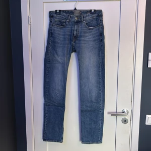 Blå regular fit jeans från Dressmann - Klassiska blå jeans från Dressmann i regular fit med raka ben och femficksdesign. Jeansen är tillverkade i slitstark bomull och har en tidlös look som funkar till det mesta. Perfekta för dig som gillar en enkel och clean stil.