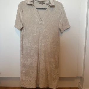 Beige kortärmad klänning - Beige kortärmad klänning från H&M i storlek XS. Modellen är rak och slutar strax ovanför knäna. 