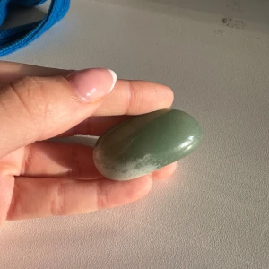 Grön polerad sten - En slät, grön polerad kristall med ljusare inslag. Den har en mjuk, oval form
