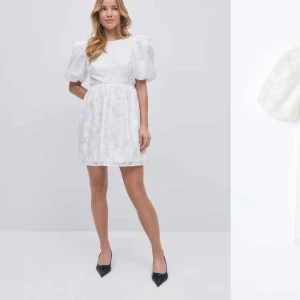 Vit studentklänning med puffärmar och öppen rygg - Superfin vit kortklänning med puffiga ärmar! Klänningen har ett  blommigt mönster, öppen rygg med knyt🌸Köpt på Vinted i nyskick, endast provad av mig! Nypris 600 kr🩷