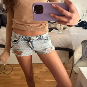  jeansshorts - Säljer ett par ljusblå jeansshorts med slitna detaljer och fransar. Shortsen har klassisk femficksmodell, låg midja och råa kanter 💕💕💕