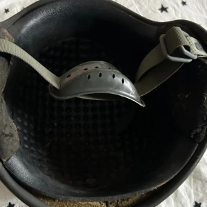 Grön militärhjälm med hakrem - Säljer en klassisk grön militärhjälm med justerbar hakrem och vadderad insida. Hjälmen har en robust utsida och är designad för att ge extra skydd vid aktiviteter som kräver hjälm. Har 2 st. Priset siter inte i sten.