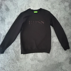 Svart sweatshirt från Hugo Boss - Svart tröja från Hugo Boss med loggan på framsidan.