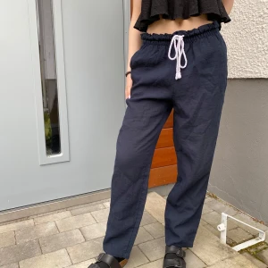 Mörkblå linnebyxor - Säljer ett par mörkblå linnebyxor med vit snörning i midjan. Byxorna har avslappnad passform och resår i midjan för extra komfort. Perfekta för en chill och stilren look. Kontakta för frågor eller fler bilder💞 priset kan diskuteras vid snabb affär⭐️