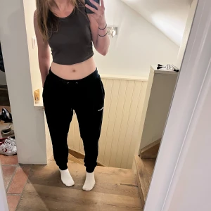 Svarta mjukisbyxor från Ellesse - Svarta mjukisbyxor från Ellesse med broderad logga på benet. Byxorna har dragsko i midjan och är tillverkade i ett mjukt, plyschtyg material. Passar på mig och jag är 165 cm lång även om storleken är XL. Perfekta för en avslappnad stil och riktigt sköna att ha på sig.