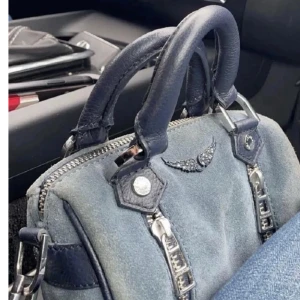 Blå handväska med silverdetaljer - Säljer en snygg blå handväska från Zadig Voltaire,med dubbla handtag och utan axelband. Väskan har två dekorativa silverdragkedjor framtill och en liten logga i silver. Tillverkad i mocka och skinn med mörkblå detaljer.💕