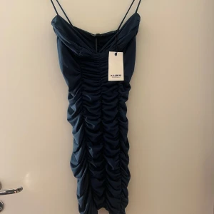 Mörkgrön klänning från Pull&Bear - Säljer en mörkgrön klänning från Pull&Bear med smala axelband och rynkad framtill. Klänningen har en djup v ringning och är figurnära. Skriv för fler bilder!