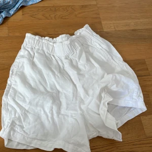 Vita linneshorts från Everme - Säljer ett par vita shorts från Everme i luftig linnekvalitet. De har resår i midjan för extra komfort och en avslappnad passform. Perfekta för varma dagar och enkla att matcha med olika toppar.