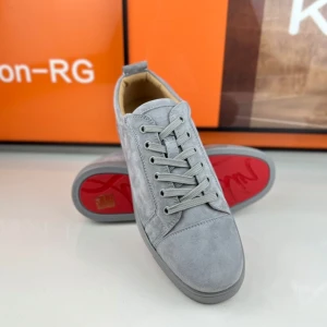 Grå sneakers med röd sula - Snygga grå sneakers med ovandel i mocka och klassisk snörning. Skorna har en unik röd sula och diskreta metalldetaljer på sidan. Perfekta för dig som vill ha en stilren men ändå iögonfallande look.