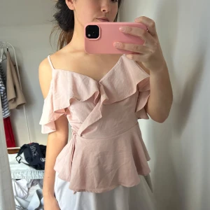 Ljusrosa volangtopp med knytband - Supersöt ljusrosa topp med volangdetaljer och omlottkänsla. Toppen kan man ha på två sätt (de bilder)