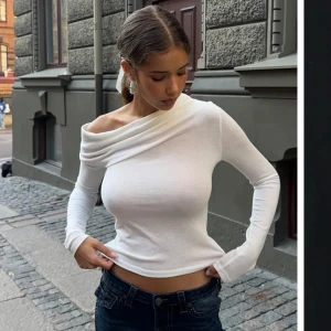Vit offshoulder långärmad topp - Säljer en vit långärmad topp med offshoulder-design och smal passform. Toppen har en snygg asymmetrisk halsringning och är tillverkad i ett mjukt bomullsliknande material. Perfekt att styla med jeans eller kjol.