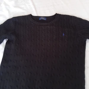 Svart kabelstickad tröja från Polo Ralph Lauren - Dethär är en Polo Ralph Lauren tröja som är svart stickad,är väldigt skön att ha på sig, är i ett bra skick och är i storlek S.En bra sommar tröja för ett dunder pris, meddela mig om du vill ha mer information. 