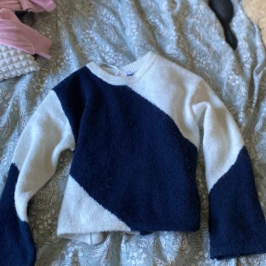 Vit och marinblå stickad tröja från Gina Tricot - Säljer en mysig stickad tröja från Gina Tricot i storlek 134/140. Tröjan har ett coolt diagonalt mönster i vitt och marinblått, rund halsringning och långa ärmar. Perfekt för dig som gillar en stilren men ändå unik look.