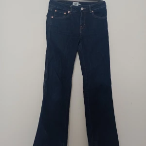Mörkblå bootcut jeans - Säljer ett par mörkblå bootcut jeans från Lager 157 i storlek XS och short längd. Klassisk femficksmodell med knapp och dragkedja framtill. Perfekta för dig som gillar en tidlös jeanslook med lite utsvängda ben.