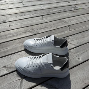 Vita sneakers från Philippe Model - Säljer ett par fräscha vita sneakers från Philippe Model med svarta detaljer på hälen. Ett sjukt bra val till sommaren. Jätte bra skick. Nypris ca 3500kr