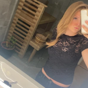 Svart spetsblus från Hollister - Säljer en svart blus från Hollister i genombruten spets. Blusen har korta ärmar. Perfekt för dig som vill ha en stilren men ändå detaljrik topp. I toppen sitter det fast ett linne!! Storleken saml och sparsamt använd💓