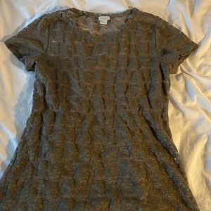 Grön spetstopp från H&M - Säljer en grön kortärmad spetstopp från H&M. Toppen är tillverkad i ett vackert spetsmaterial och har en rund halsringning. Perfekt för dig som gillar en feminin och stilren look.