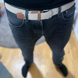 Beige flätat bälte med bruna skinn-detaljer - Snyggt beige flätat bälte med bruna skinn-detaljer och silverfärgat spänne. Perfekt accessoar för att lyfta din outfit. Bältet har en stilren design och passar till många olika looks. Aldrig använt! Nytt skick!