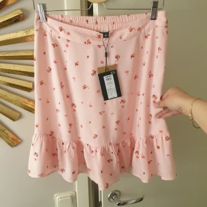 Kjol  - Jättefin rosa kjol med små blommor och jordgubbar. Helt ny med lappen kvar. 