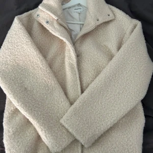 Beige teddyjacka från Kappahl  - Mysig beige teddyjacka med hög krage och dragkedja. Jackan har lång ärm och är tillverkad i ett fluffigt teddy-material. Köpte den för 1000 endast använd 1 gång 