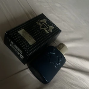 Parfums de Marly Layton Eau de Parfum - Exklusiv herrparfym från Parfums de Marly, Layton. Flaskan är matt mörkblå med ingraverade hästar och guldfärgad kork. Doften är elegant och lyxig, inspirerad av 1700-talets franska hov. Köpt för 3000kr. Flaskan är 125ml och det är lite mer än halva flaskan kvar. 