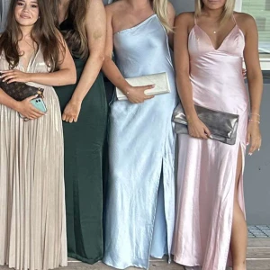 Balklänning - Säljer min satin ljusblå balklänning! Asymetrisk överdel med smala axelband som är öppen i ryggen, skriv privat för fler bilder! Finns även en slits på vänster sida! Jag är 162 och hade 5 cm klackar på balen, skulle säga att klänningen passar en storlek S