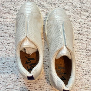 Vita slip-on sneakers med ormmönster - Säljer ett par vita slip-on sneakers med snyggt ormmönster. Helt oanvända säljer billigt har för mycket skor 