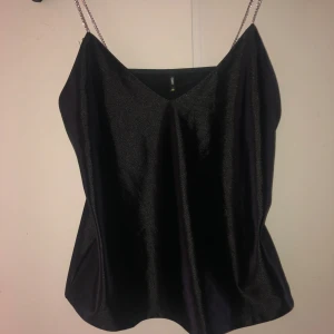 Svart satin linne med diamantband från ONLY  - Säljer en festlig svart satin topp med tunna diamantband och v-ringning. 