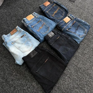Ett bunt Nudie jeans  - Sex par jeans i olika blå och svarta nyanser. Modellerna har klassiska femficksdetaljer och läderpatch bak i midjan. Finns i storlekar W28-L30, W28-L34, W30-L34, W31-L32, W32-L34. Perfekta för dig som gillar jeans med olika tvättar och passform.
