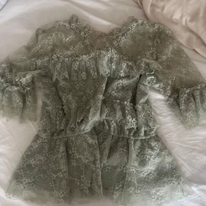 Ljusgrön spets blus med volanger -  ljusgrön blus i spets med volangdetaljer och trekvartsärm. Klänningen har en feminin siluett och är perfekt för vårens och sommarens tillfällen. Sitter som M/S