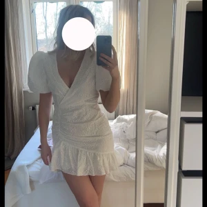 Vit puffklänning - Superfin vit kortklänning med omlott-look, puffärmar och volang nertill. Klänningen har broderade detaljer och v-ringning, perfekt för sommarens tillfällen. EU 40 men passar mig som har 36-38, aldrig använd 