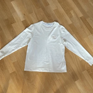 Vit långärmad tröja från Calvin Klein Jeans - Säljer en stilren vit långärmad tröja från Calvin Klein Jeans med diskret CK-logga på bröstet. Tröjan har rund halsringning och är gjord i mjuk bomull, perfekt för en clean och enkel look. Använd 1 gång då jag växt ut den lite