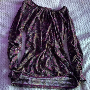 Mönstrad långärmad blus från Bik Bok - Säljer en långärmad blus från Bik Bok i storlek S. Blusen har ett paisleymönster i lila, rosa, gult och svart med inslag av vitt. Den har en lös passform och är tillverkad i ett mjukt syntetmaterial. Perfekt för dig som gillar färgstarka och unika plagg!