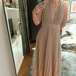 Goddiva deep v neck gold dress - balklänning  - Säljer en guldglittrig/champagnefärgad långklänning från Goddiva med djup v-ringning och halterneck. Nyskick och oanvänd med lappen kvar!  Nypris: 1599kr, priset går att diskutera  Storlek uk 10 (M/38) men passar bra på mig som brukar ha S. Banden är reglerbara och midjan stretchig så går att anpassa. 