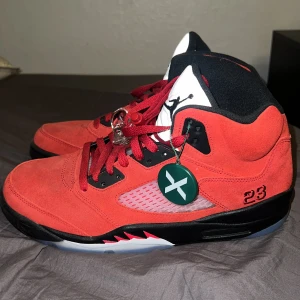 Nike Air Jordan 5 Retro Röd - Säljer ett par Nike Air Jordan 5 Retro i rött mocka med svarta och vita detaljer. Skorna har röda snören, svart sula och nummer 23 broderat på sidan. Klassisk Jumpman-logga på plösen och insidan. Perfekta för dig som gillar sneakers med attityd. Äkta också direkt från stock X