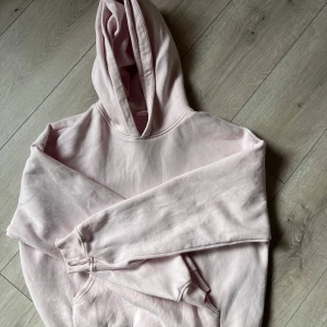 Ljusrosa hoodie - Säljer en ljusrosa hoodie med huva och magficka. Tröjan har långa ärmar och är tillverkad i mjukt bomullsmaterial. Perfekt för en avslappnad stil och enkel att matcha med jeans eller mjukisbyxor.
