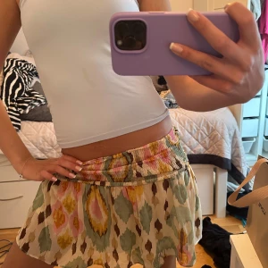 Snygg kjol - Säljer en superfin kortkjol med färgglatt mönster i grönt, gult, rosa och brunt. Kjolen har resår i midjan och är luftig med ett flowy fall. Perfekt för varma dagar och ger en bohemisk känsla till outfiten.❤️❤️