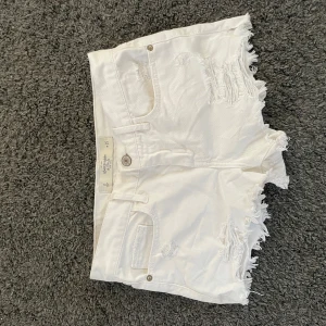 Vita jeansshorts med fransar från Abercrombie & Fitch - Säljer ett par vita jeansshorts från Abercrombie & Fitch med fransiga benslut och slitna detaljer. Shortsen har fem fickor och knappgylf. Perfekta för sommaren. 💘💓💝