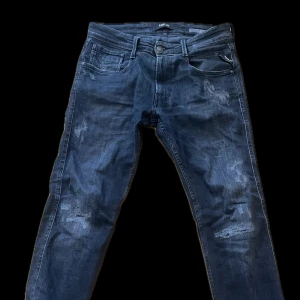 Replay jeans - Svarta jeansbyxor från Replay med slitna detaljer och klassisk femficksdesign. Perfekta för en avslappnad stil. Upplagda någon cm för en lite bättre passform