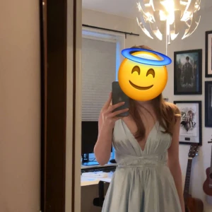 Ljusblå balklänning  - Säljer en elegant ljusblå långklänning med djup v-ringning och omlottliv. Klänningen knyts med band runt rygg och midja. Skicka privat för fler tydligare bilder. Orginalpris var 1400 kr. Är storlek 36 i vanliga fall men funkar perfekt då den har resor i ryggen :)
