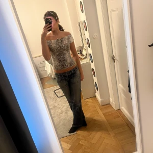 Ormmönstrad offshoulder topp - Säljer en snygg offshoulder topp med ormmönster. Toppen är tight och har en stilren design som passar perfekt för en trendig look. 