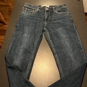 Levi's 551Z Jeans - Säljer ett par klassiska Levi's 551Z jeans i blå denim. De har en rak passform med fem fickor och den ikoniska röda Levi's-loggan på bakfickan. Perfekta för en avslappnad stil.