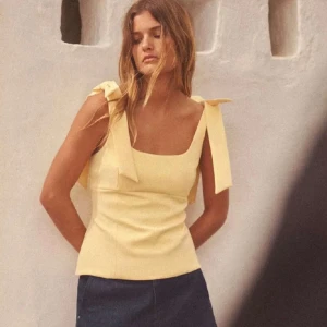 Gul  topp med rosetter från Zara - Säljer den populära gula toppen med  rosetter på axlarna från Zara!💛Perfekt för vår/sommardagar. Helt ny! Säljer då den var för liten tyvärr. Helt slutsåld på hemsidan!