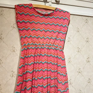 Färgglad klänning från Firefly - En rosa klänning med blå/guldiga/vita detaljer. Sparsamt använd, storlek-140cl